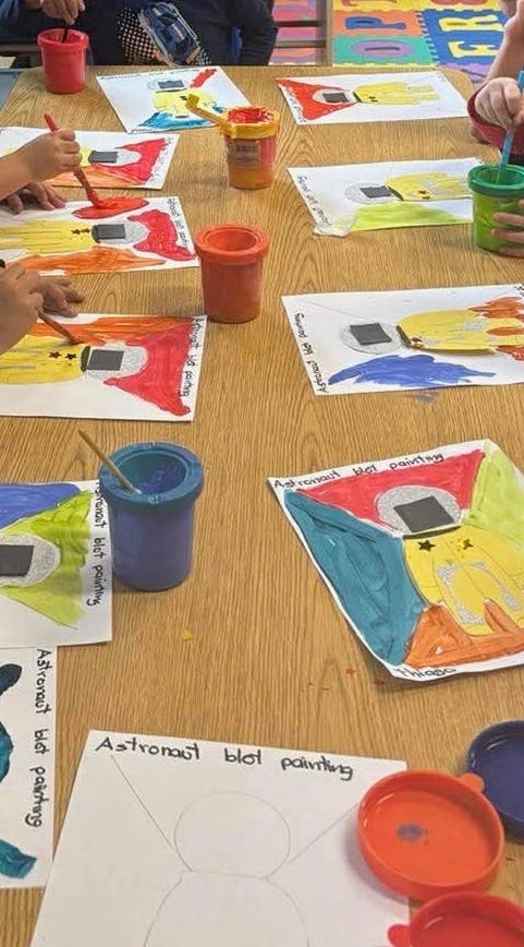 Children painting astronaut pictures at a table
