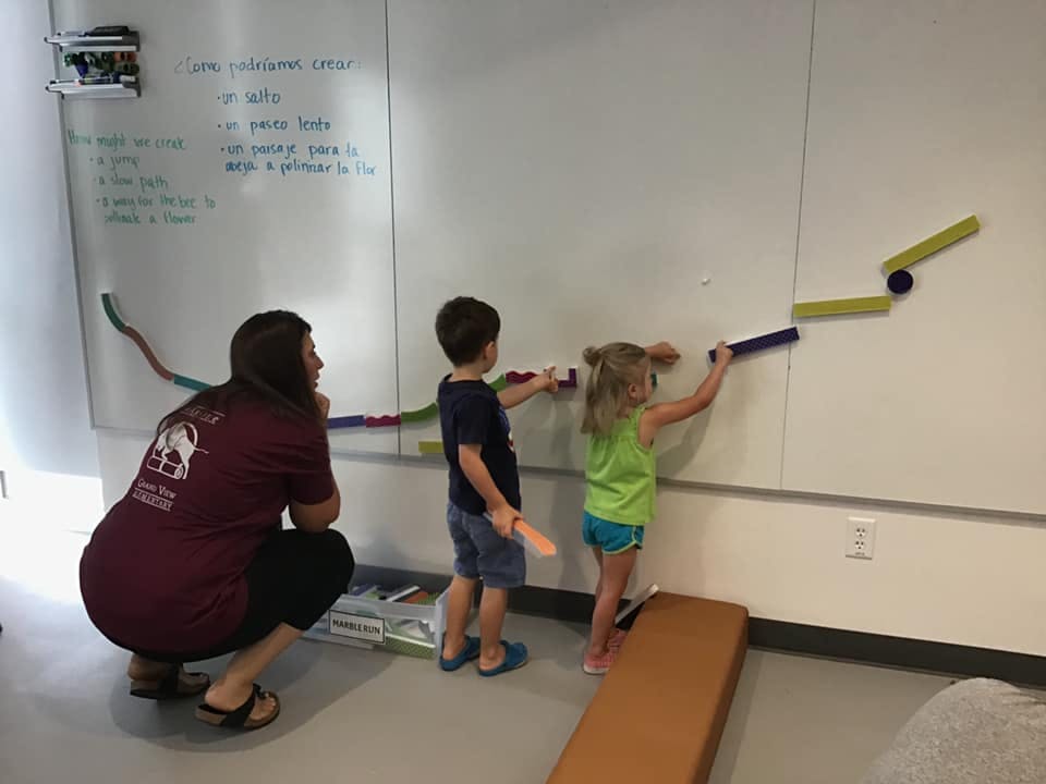 Adult and two children playing with a magnetic ball run on a whiteboard