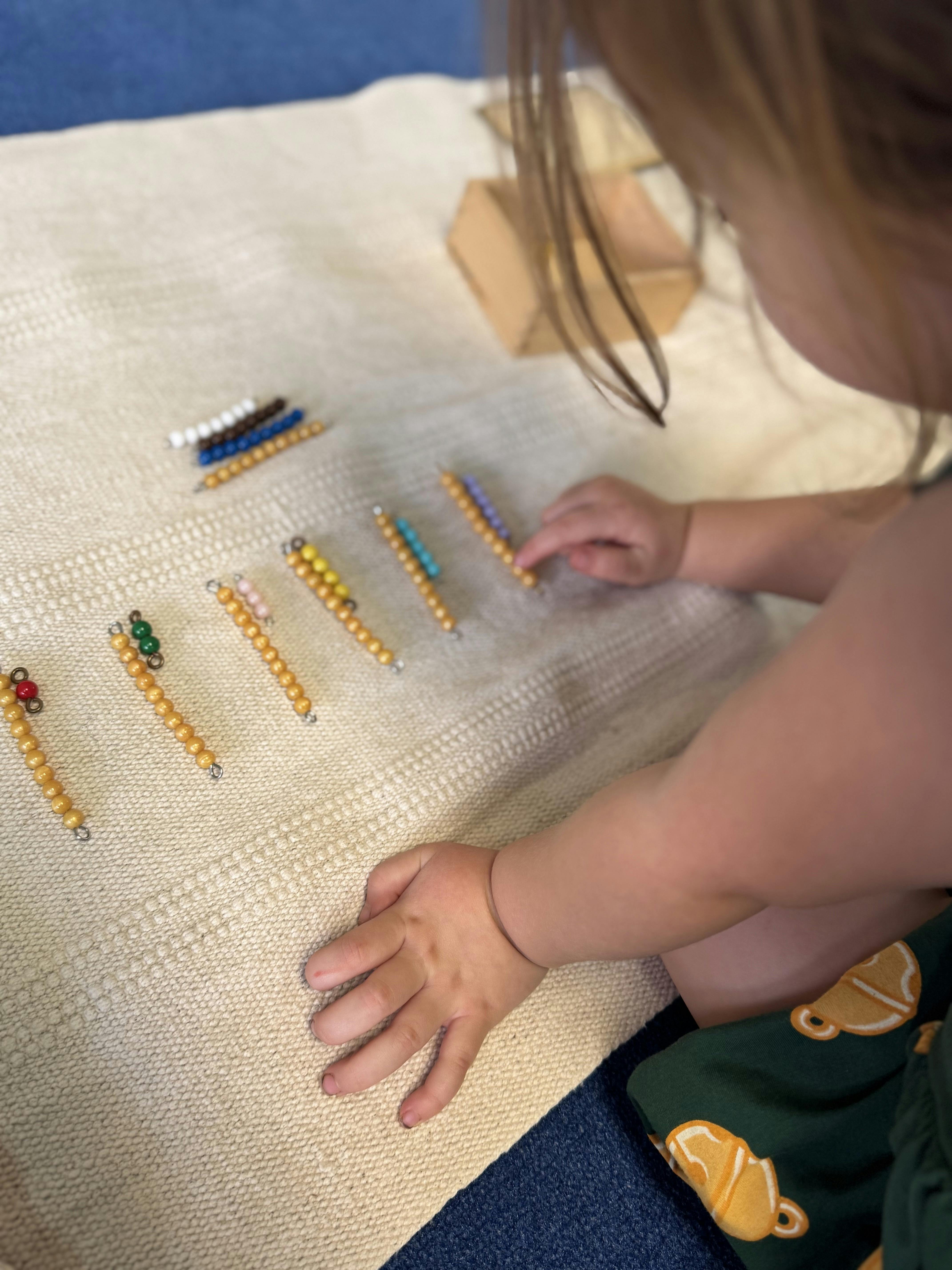 Child arranging colored bead bars on a mat
