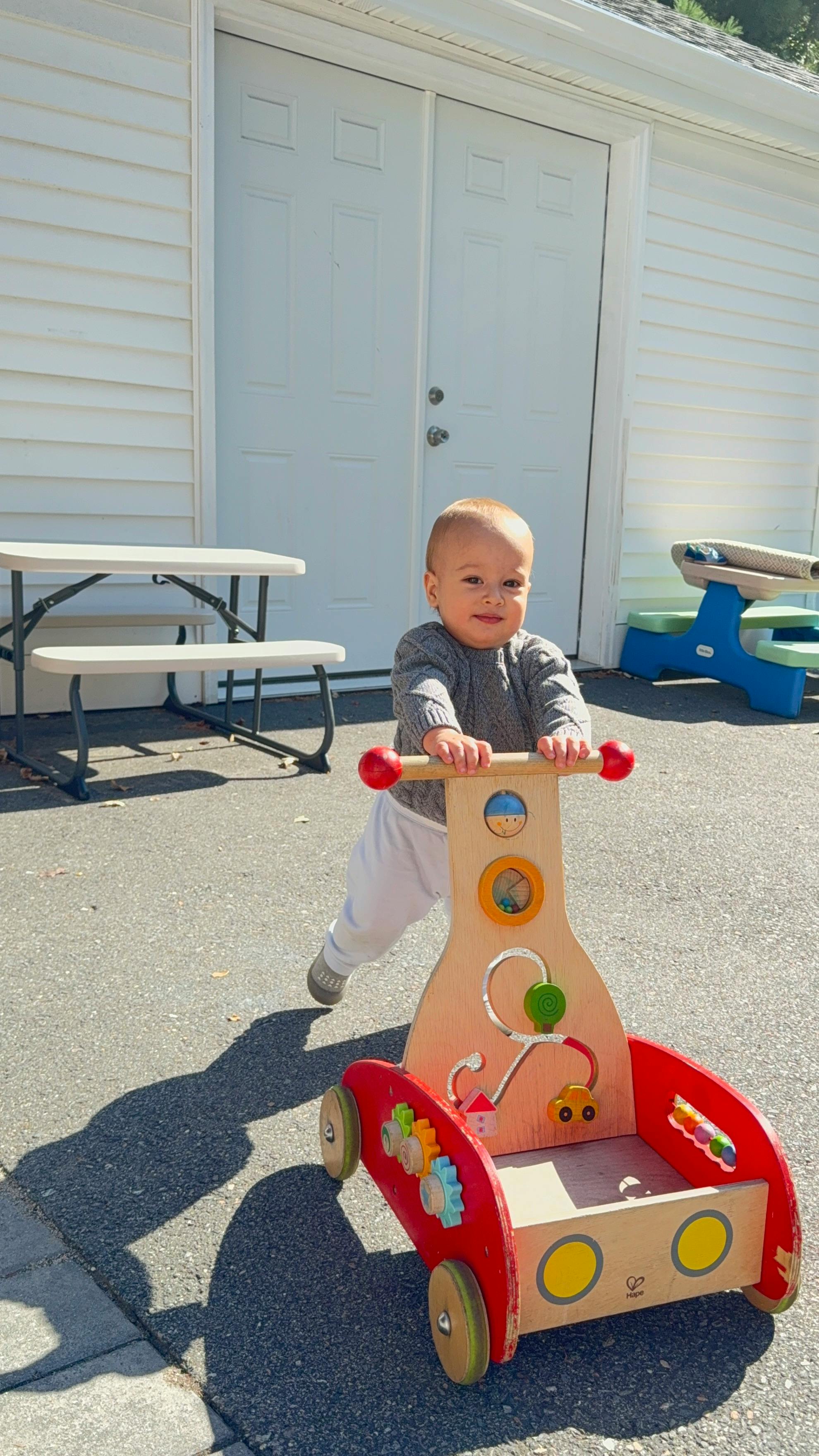Child pushing a wooden activity walker outdoors