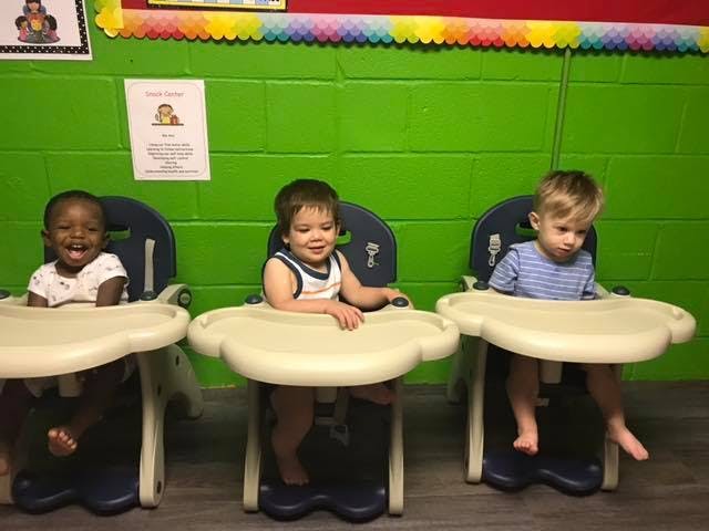 Three children sitting in high chairs