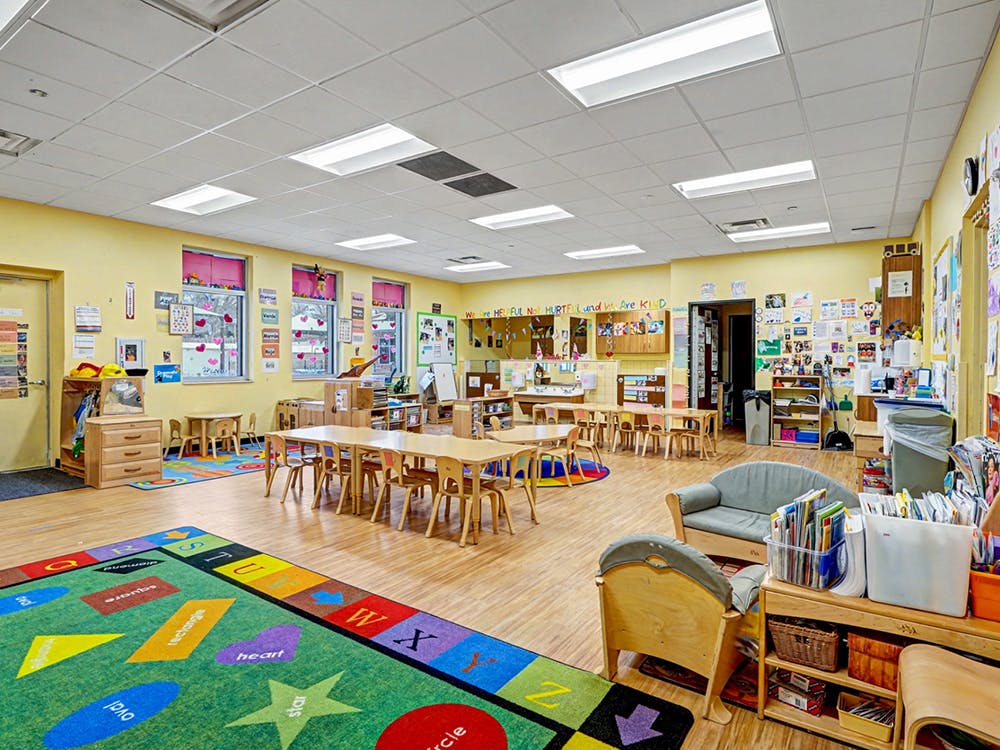 Colorful empty classroom with tables, chairs, and a rug with shapes