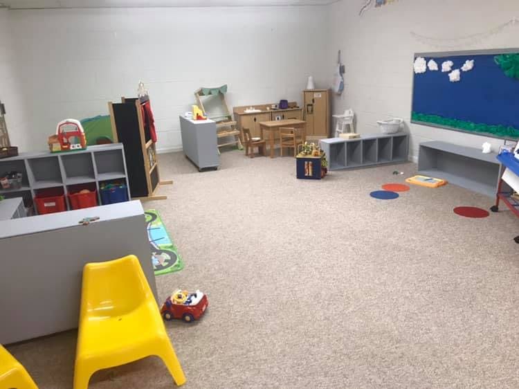 Empty classroom with small chairs, tables, and storage units