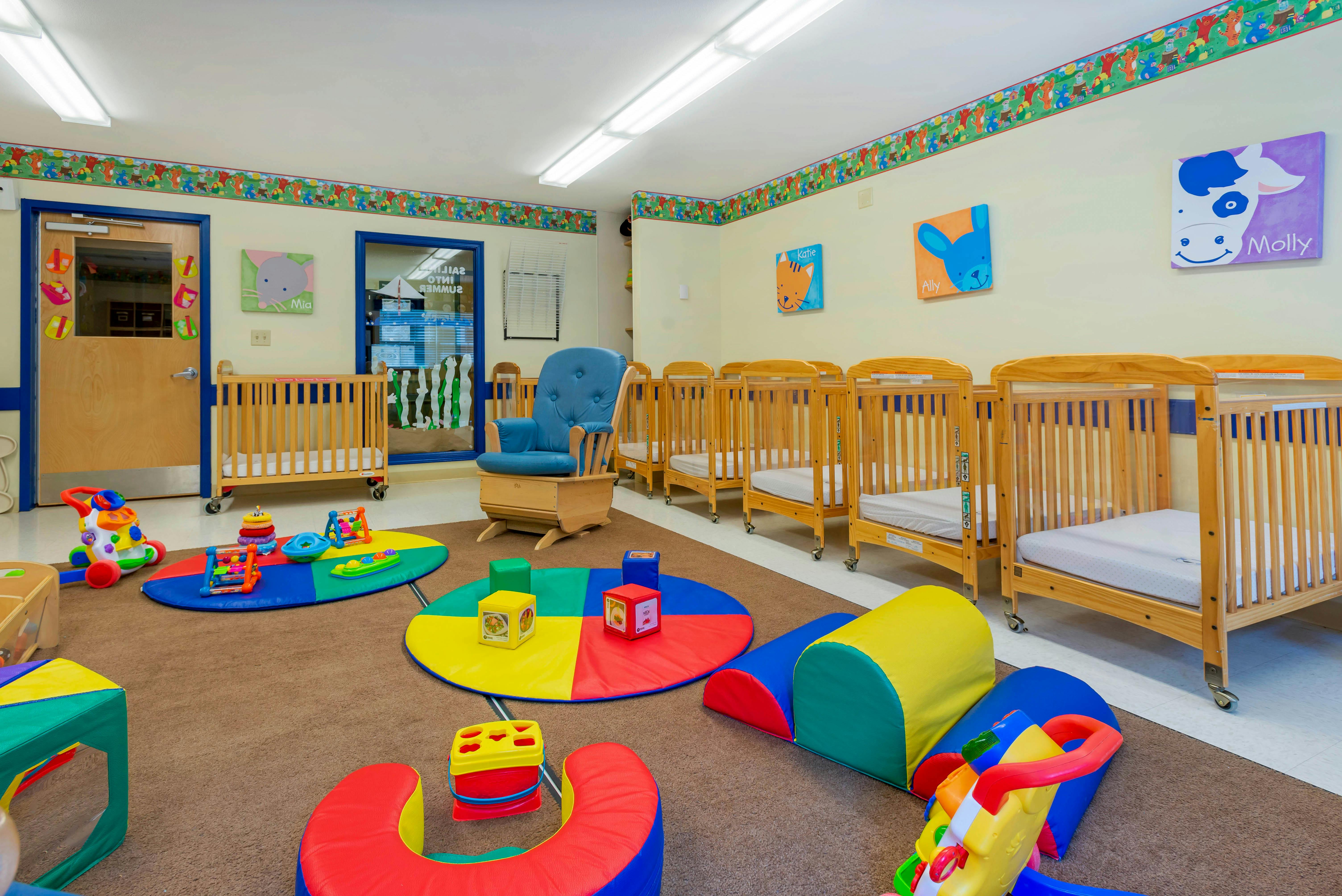 A colorful play area for young children with cribs and soft play mats