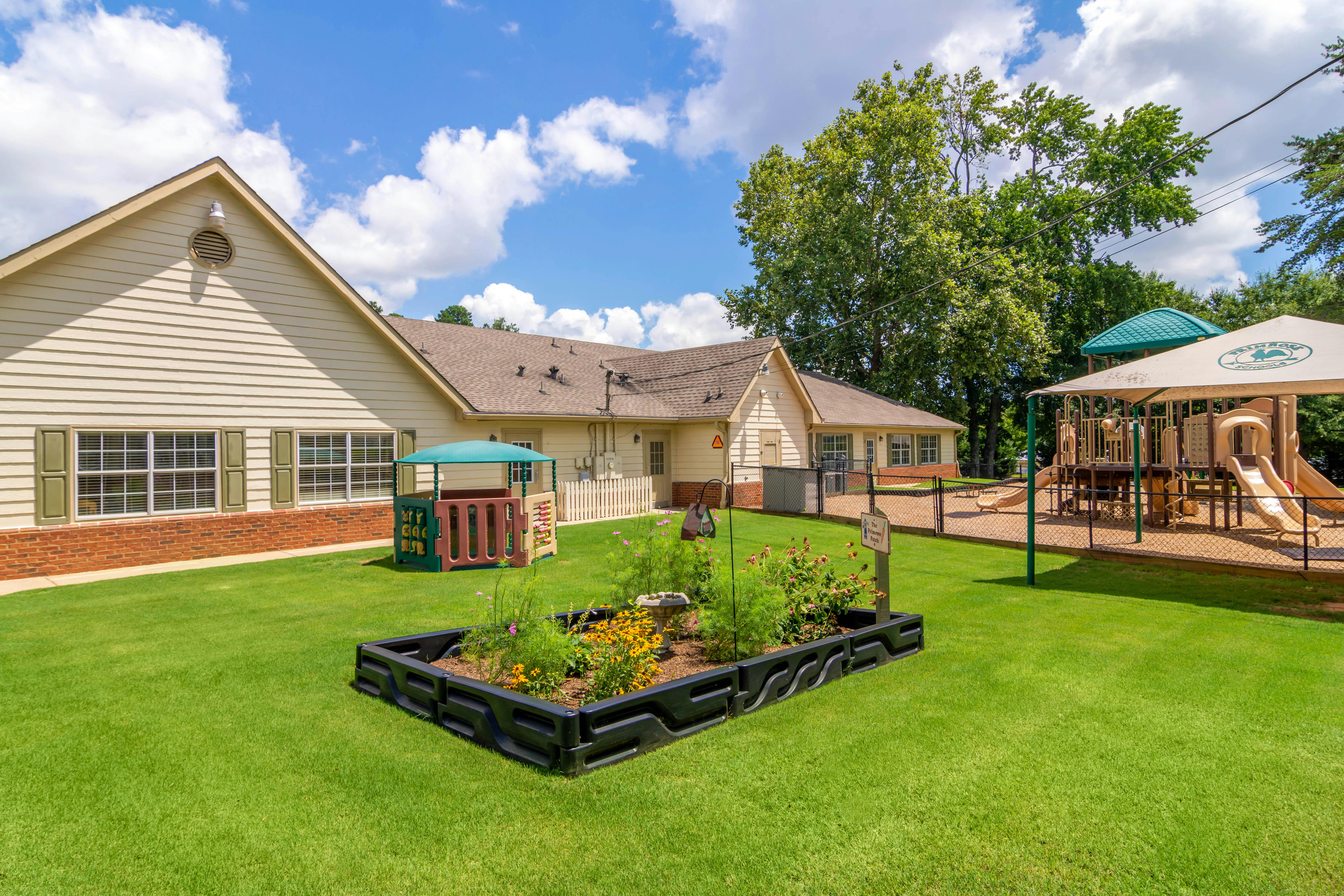 Childcare building with a playground and fenced play area in a sunny yard