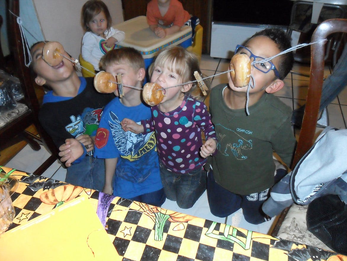 Children playing a game with donuts on a string