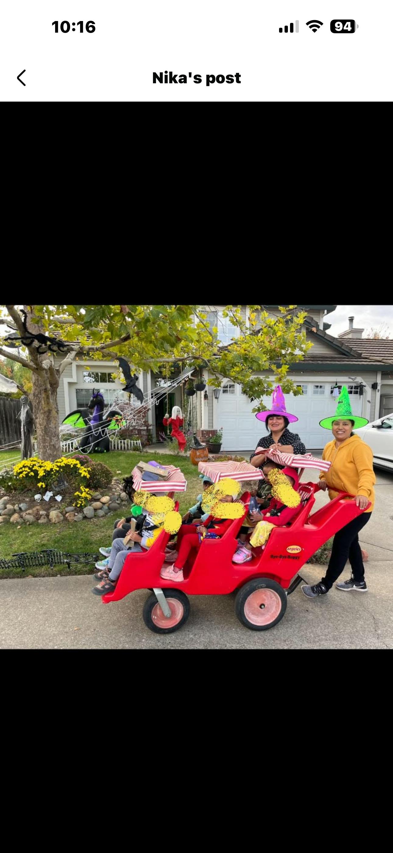 People wearing witch hats pushing children in a multi-seat red buggy