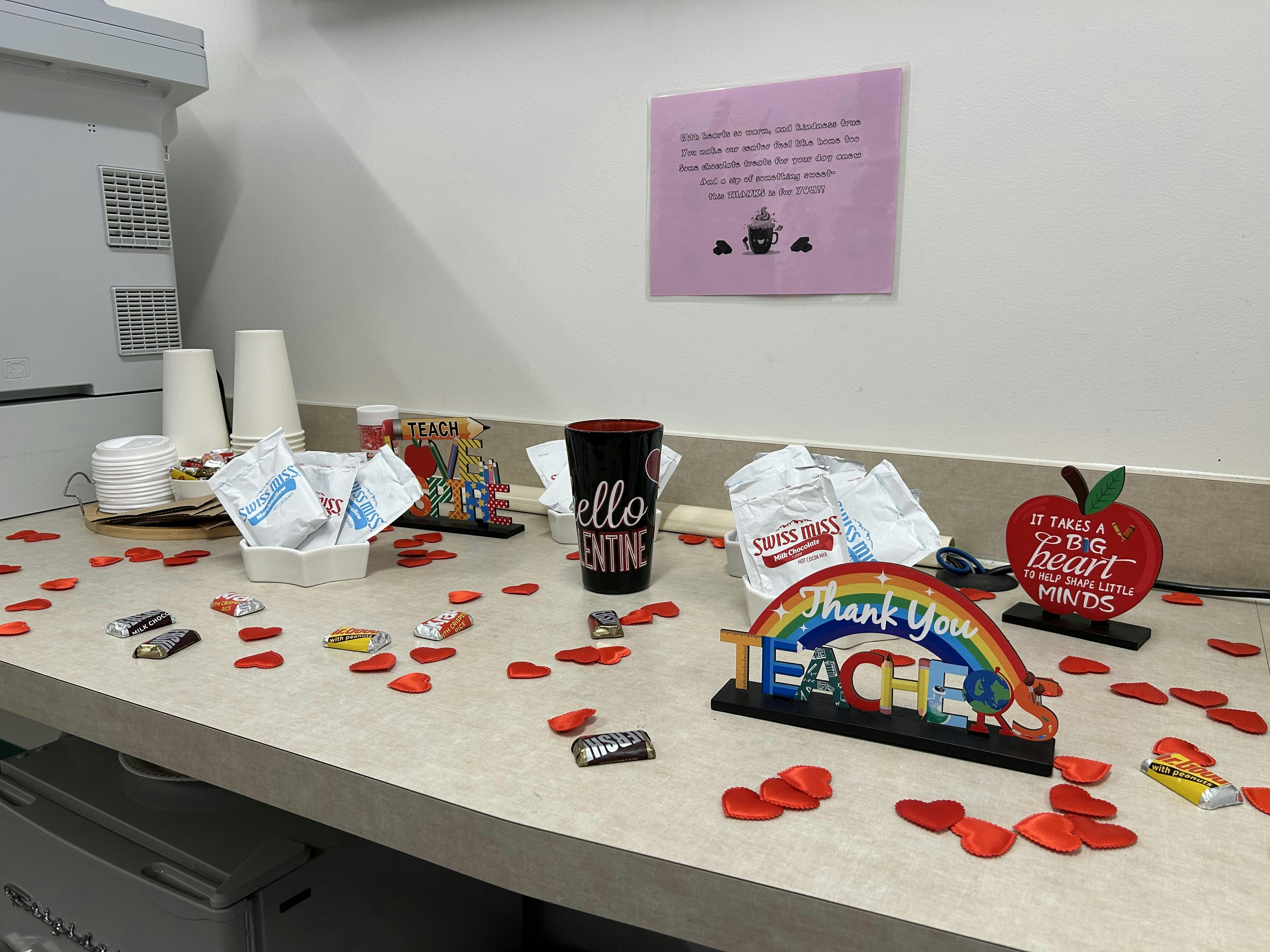 Counter with hot cocoa, chocolates, paper cups, and 'Thank You Teachers' sign