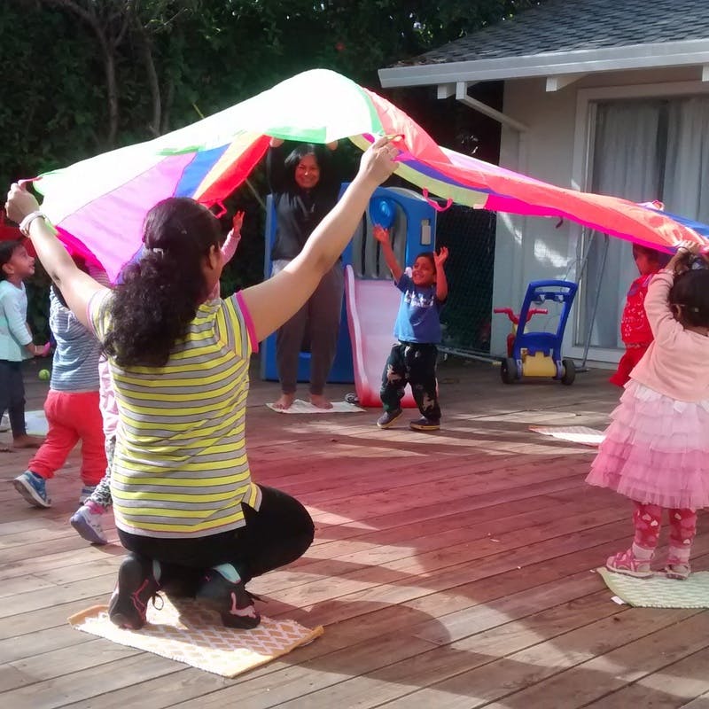 Adults and children playing with a colorful parachute outdoors