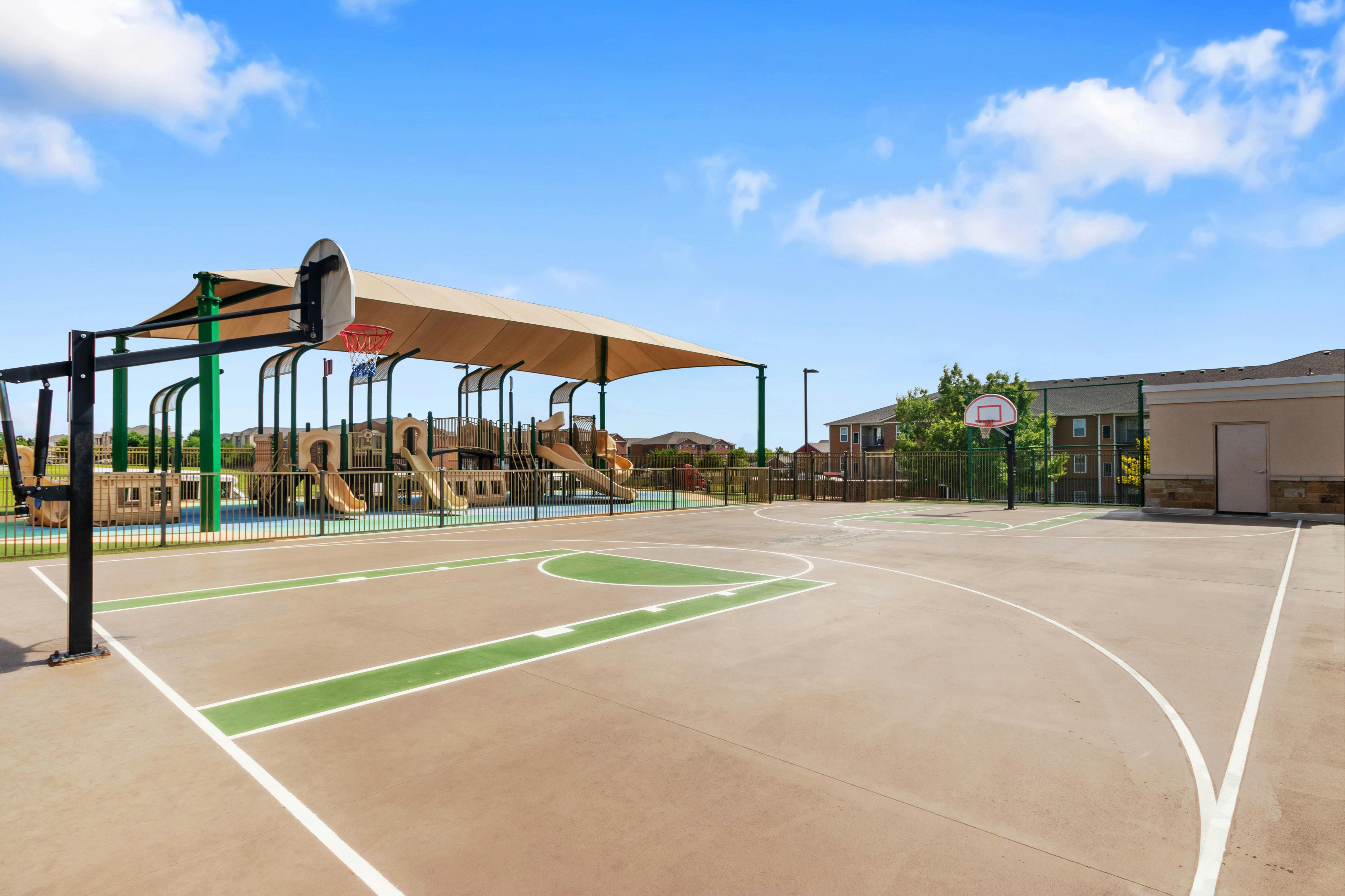 Basketball court with a playground and sunshade in the background