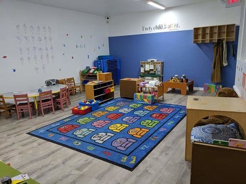 Classroom with a colorful alphabet rug, small tables, and chairs
