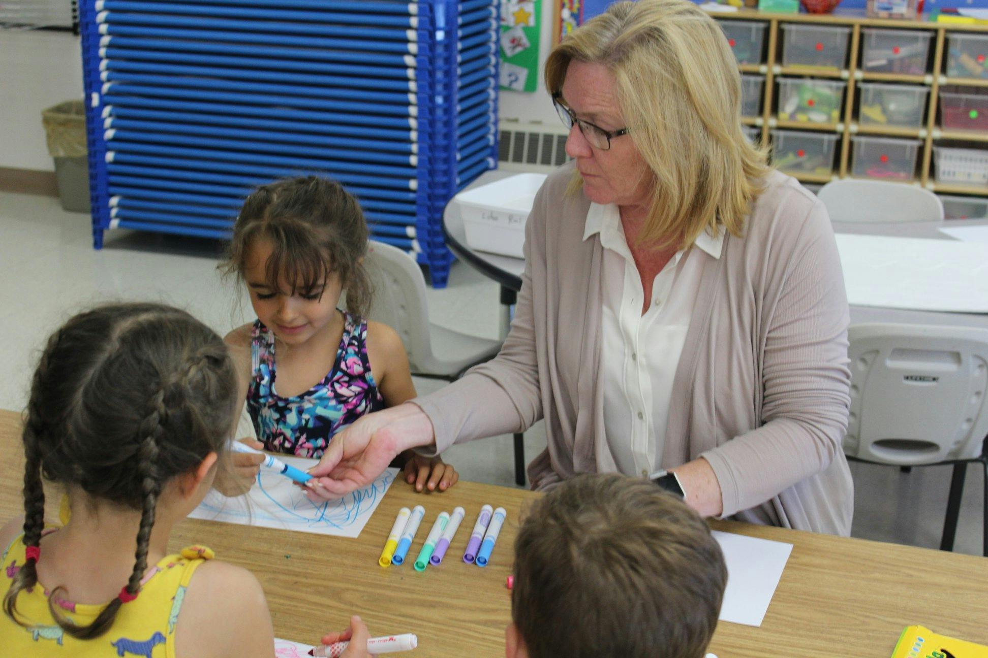 Adult and three children at a table with markers