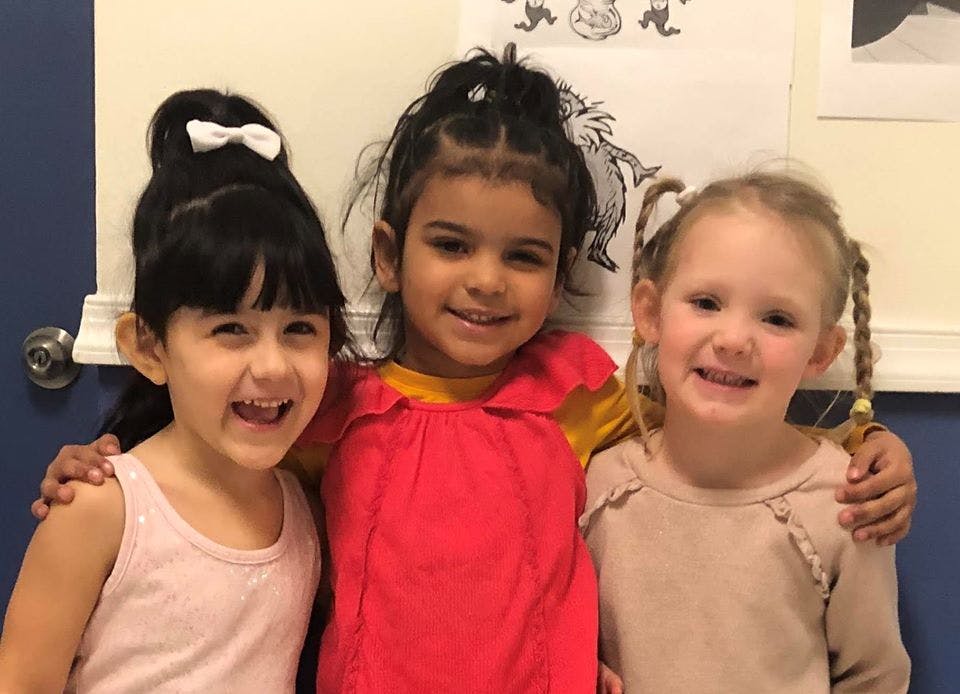 Three children smiling with arms around each other