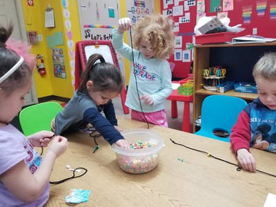 Children stringing beads in a classroom