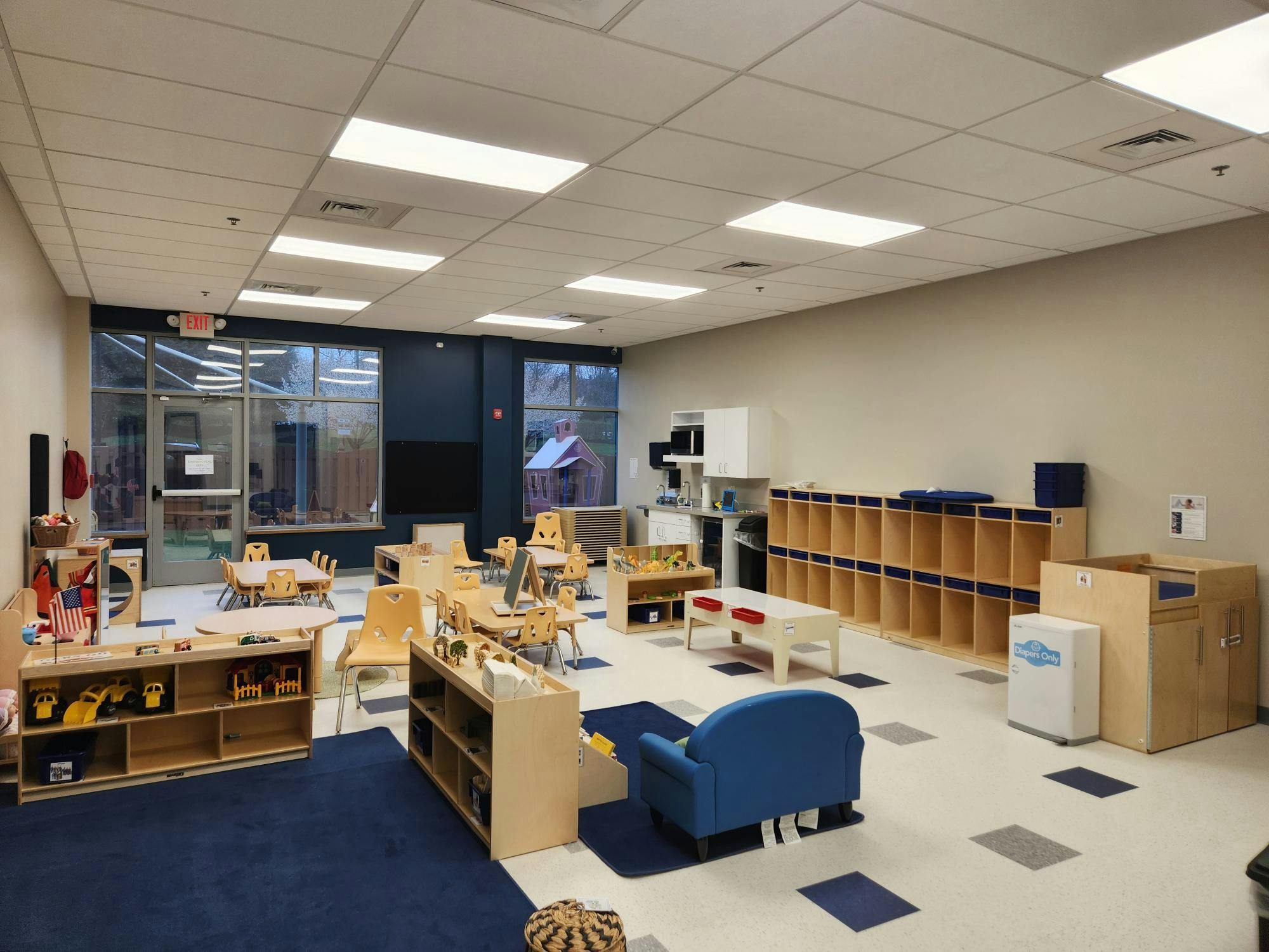 Empty classroom with small tables, chairs, and storage cubbies