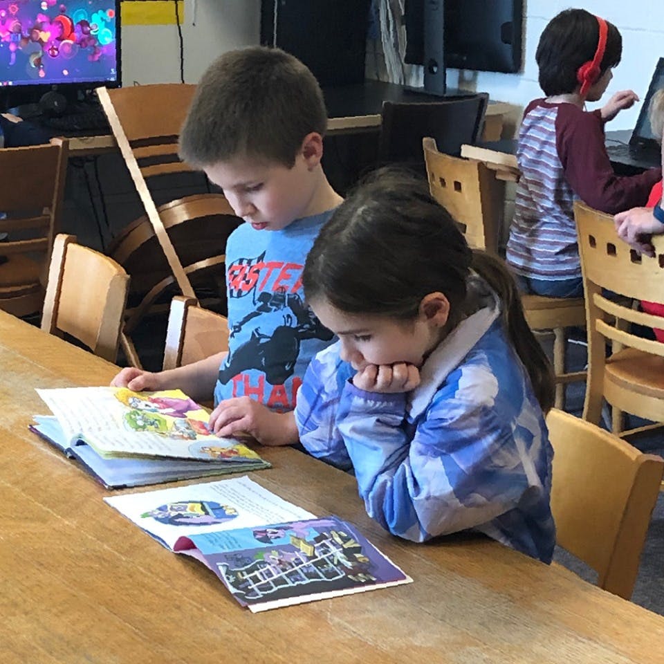 Two children reading books at a table