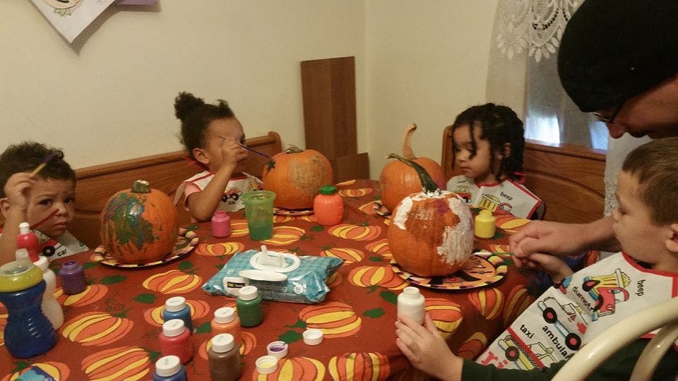 Children painting pumpkins at a table
