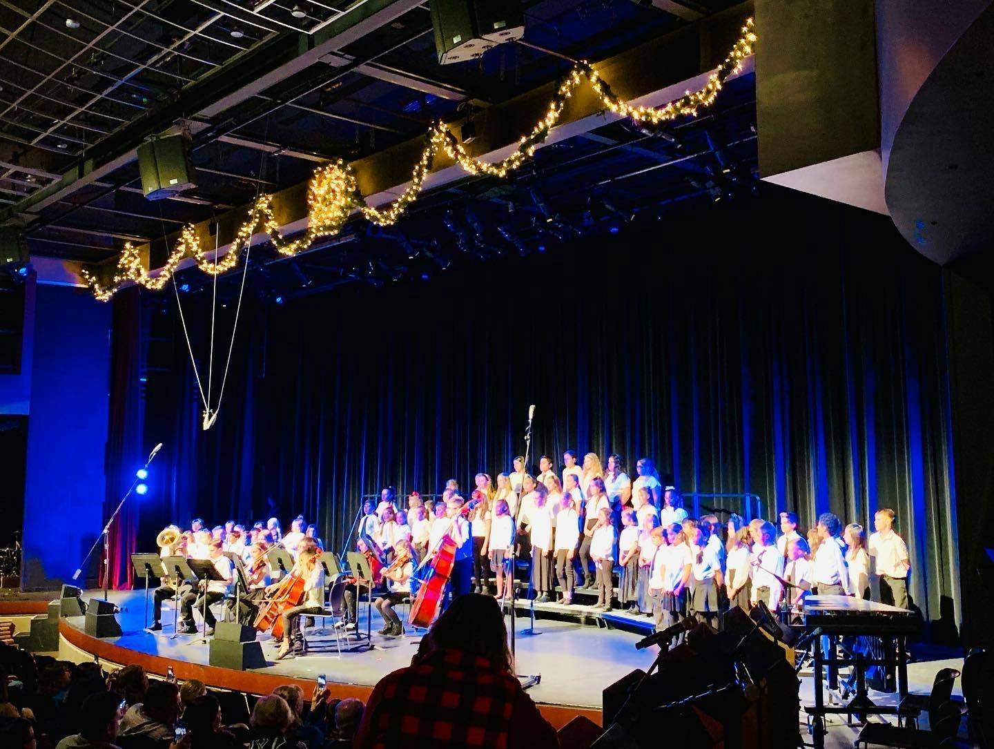 Children performing on stage with musical instruments and a choir