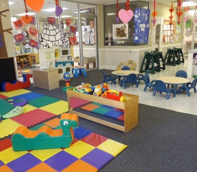 Playroom with colorful floor mats, small tables and chairs, and toys