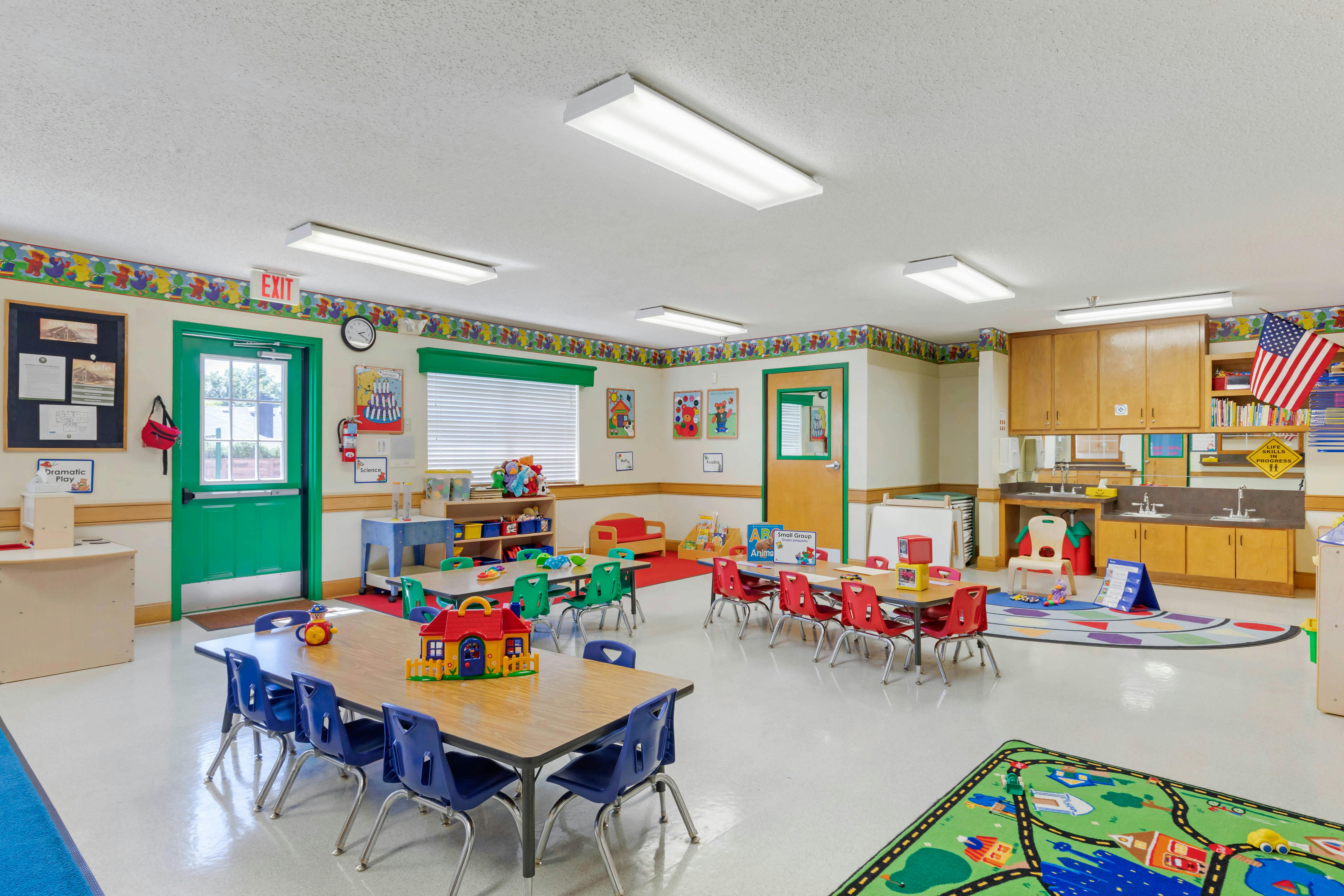 Classroom with child-sized tables and chairs, play mats, and learning materials