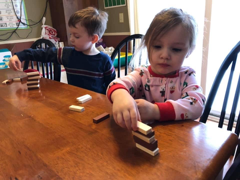 Two children playing with wooden blocks at a table