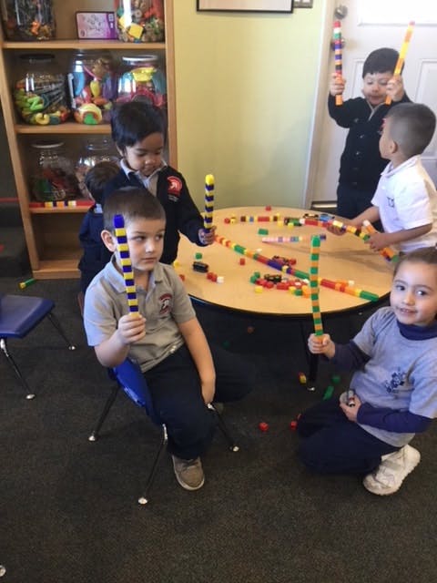 Children playing with colorful building sticks around a table