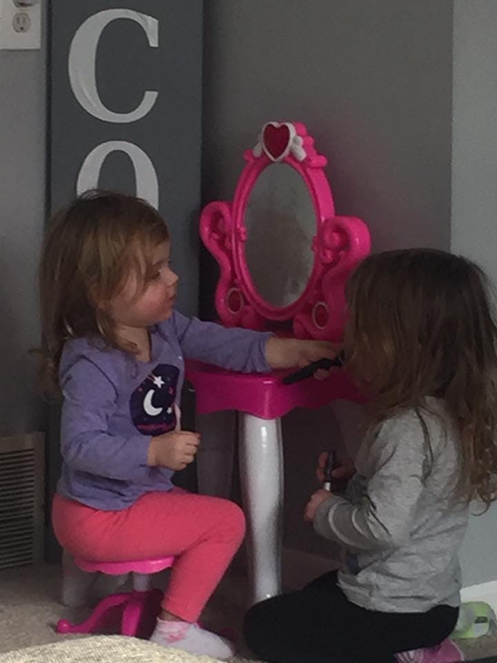 Two children playing with a pink vanity set