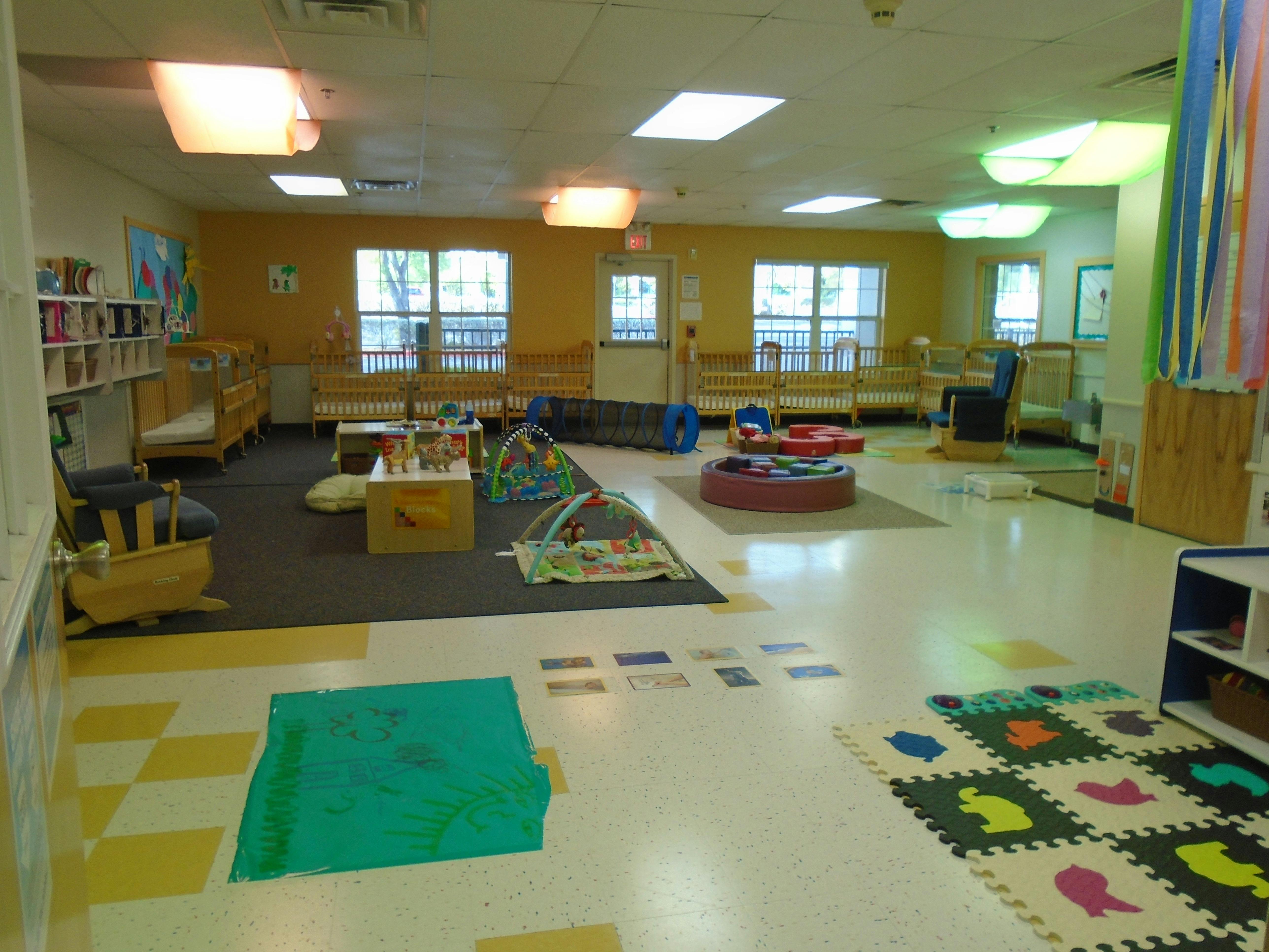 A colorful infant and toddler classroom with cribs and play areas