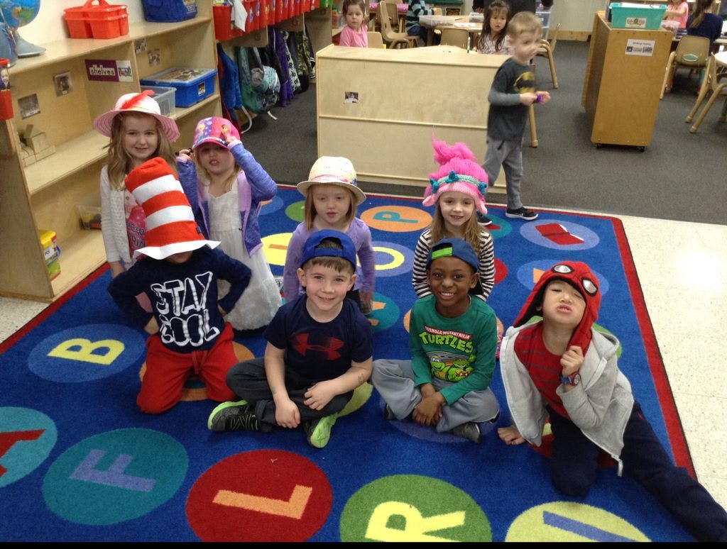 Children in a classroom wearing various hats