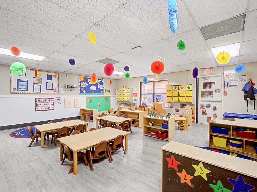Classroom with small tables and chairs, decorated with colorful paper lanterns