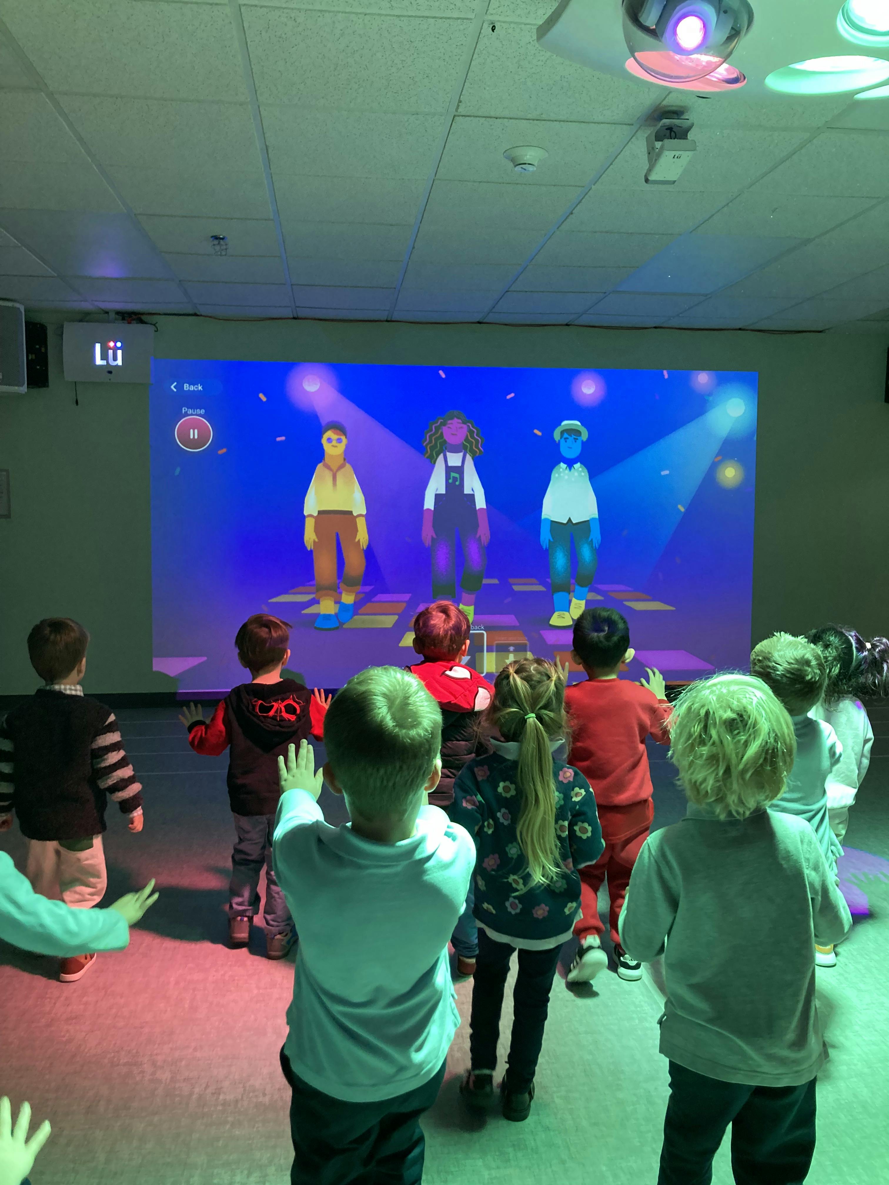 Children watching and interacting with projected animated characters on a wall