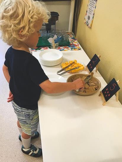 Child serving food from a bowl on a table
