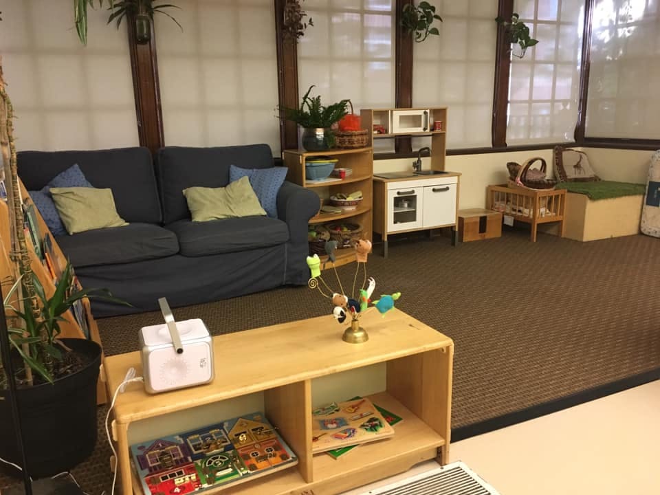 Playroom with a sofa, play kitchen, and wooden furniture