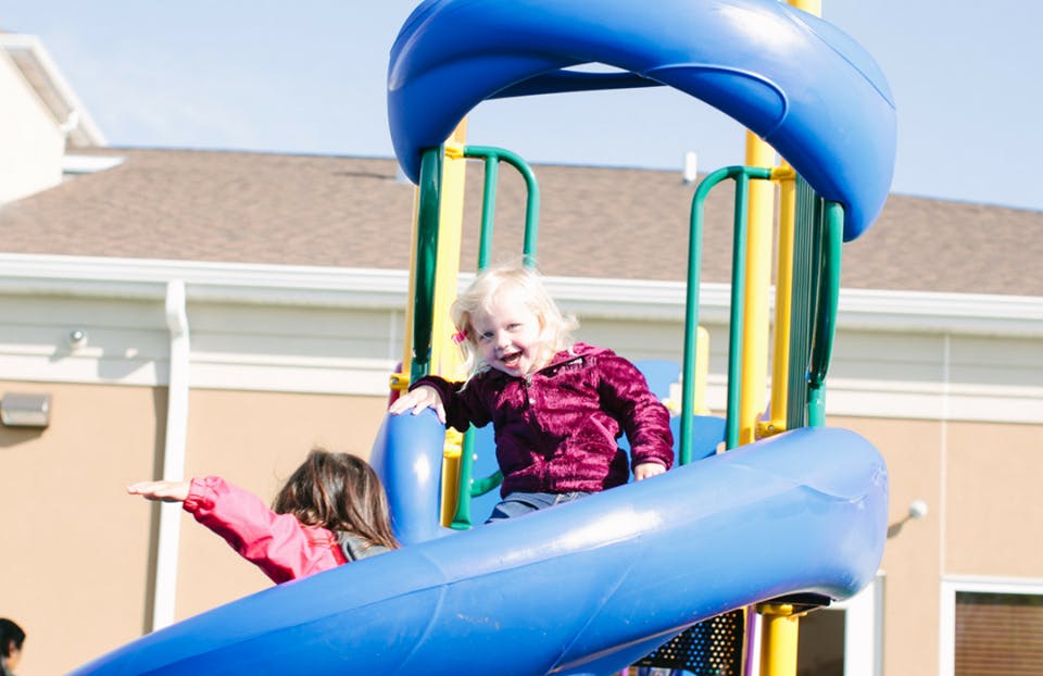 Two children on a blue playground slide