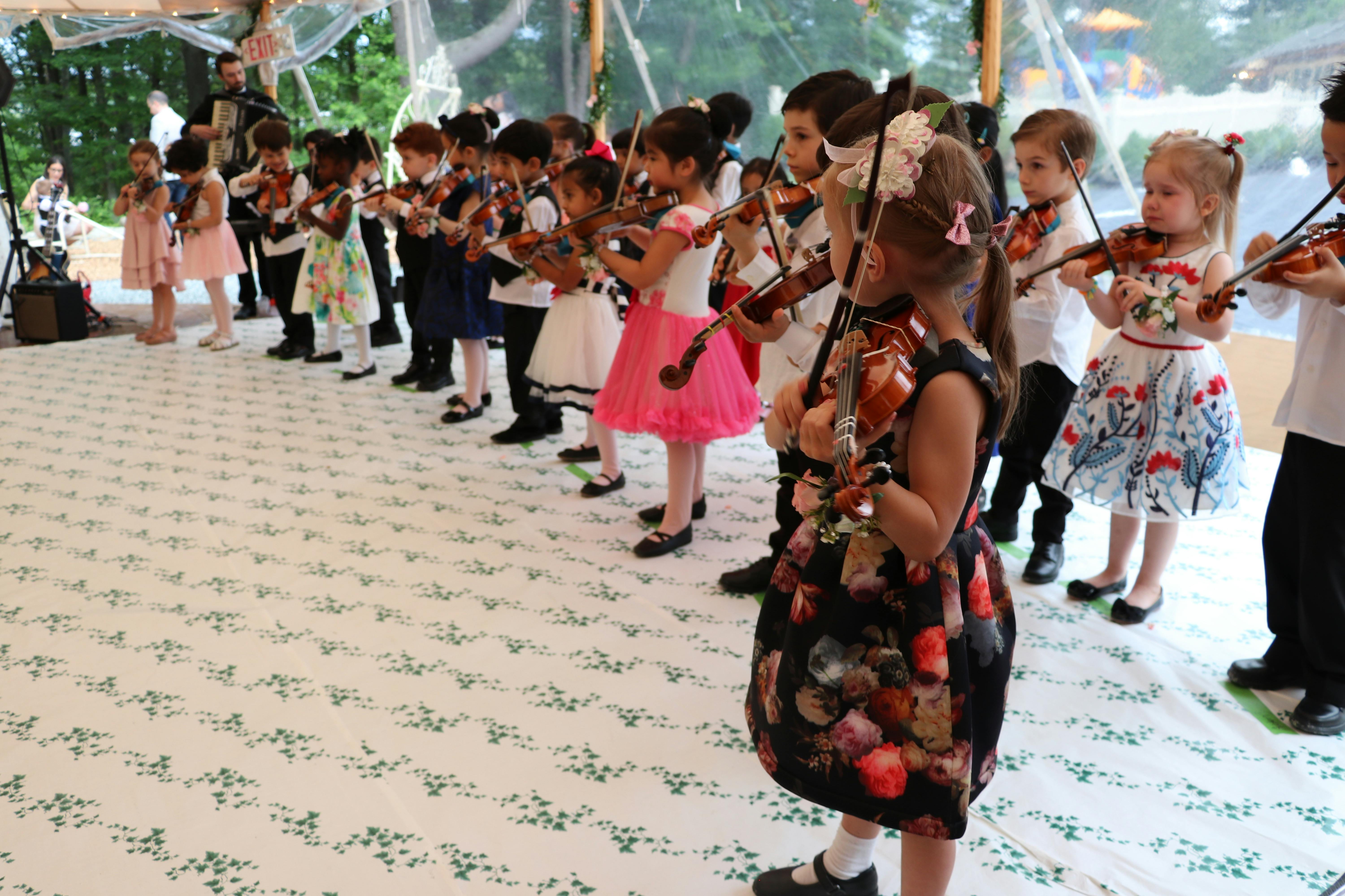 Children standing in a line playing violins
