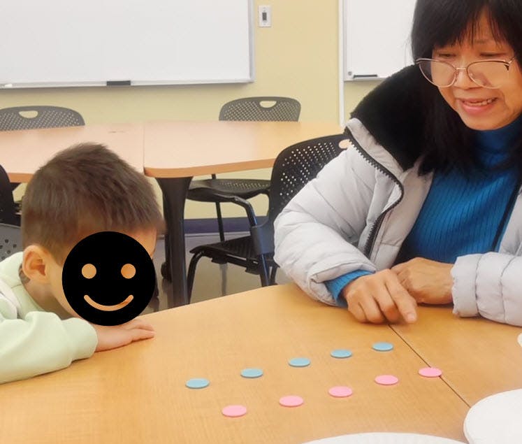 Person and child playing a game with colorful tokens on a table