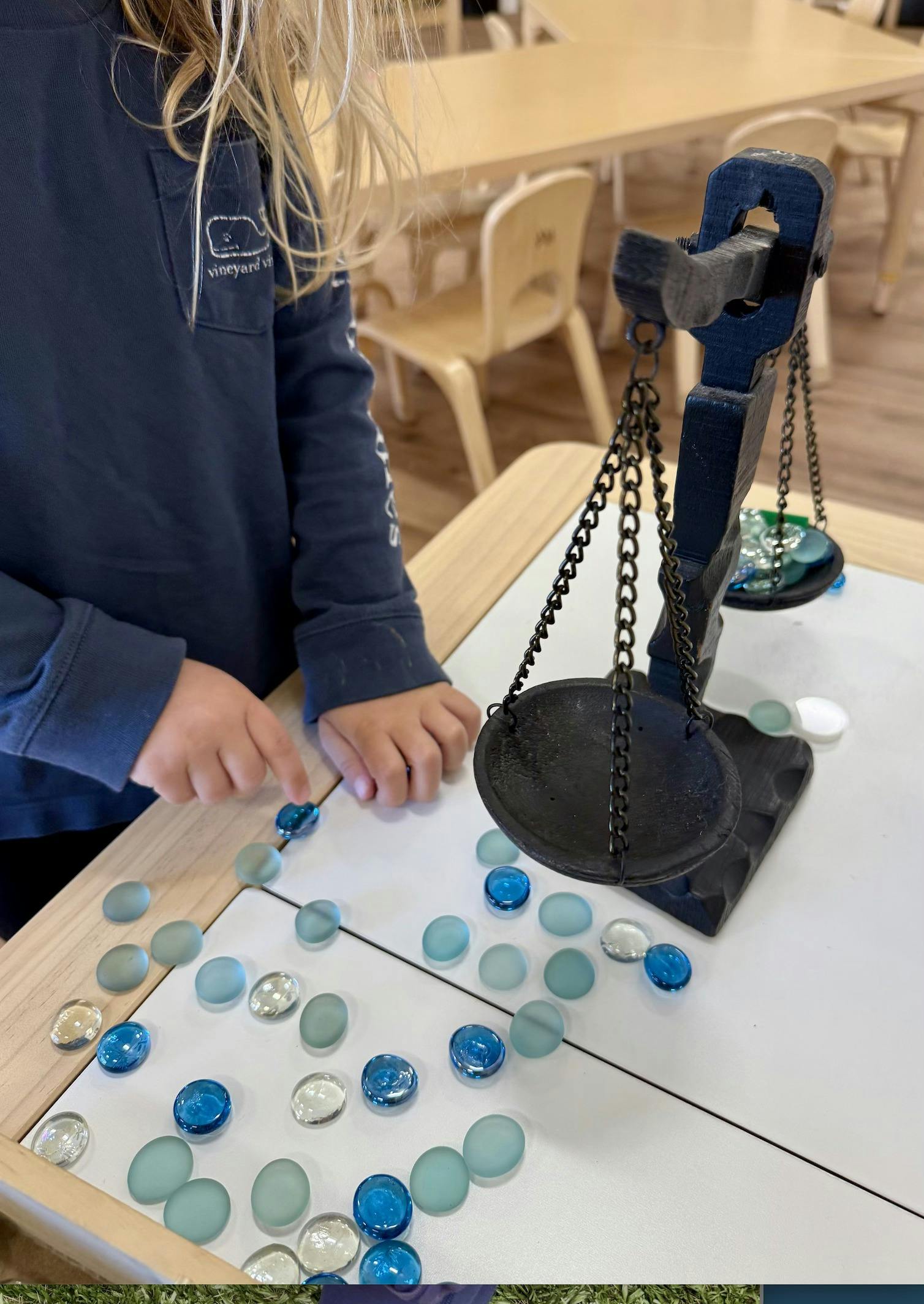 Child using a balance scale with glass beads inlays