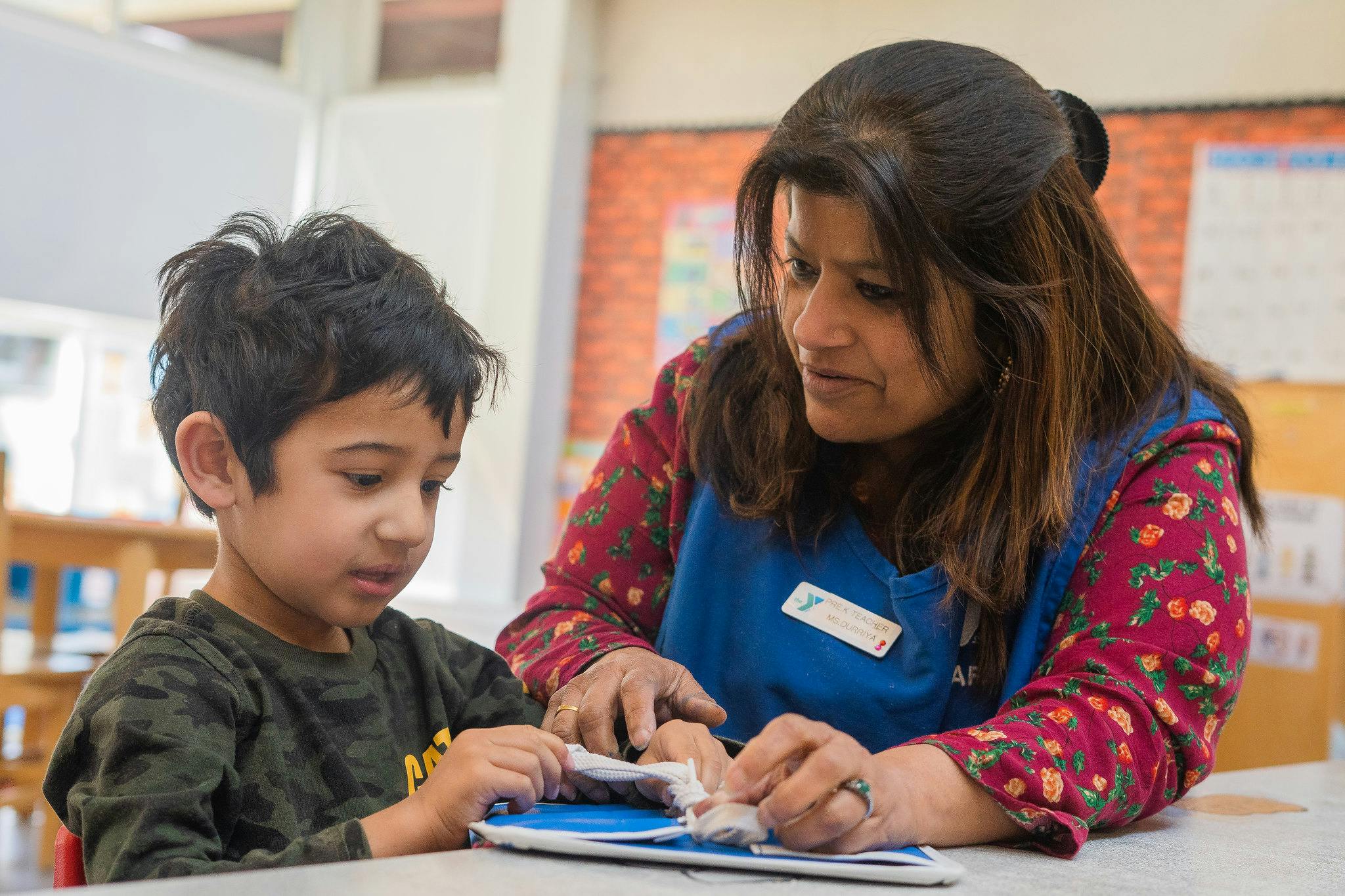 Adult and child looking at a book together in a classroom