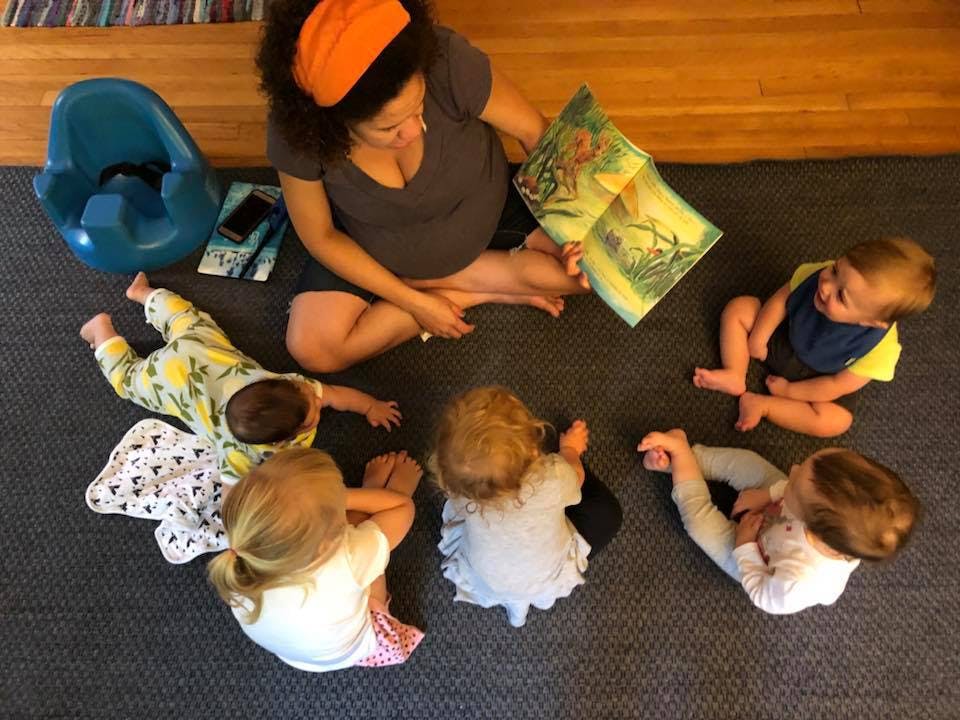 Person reading a book to four children