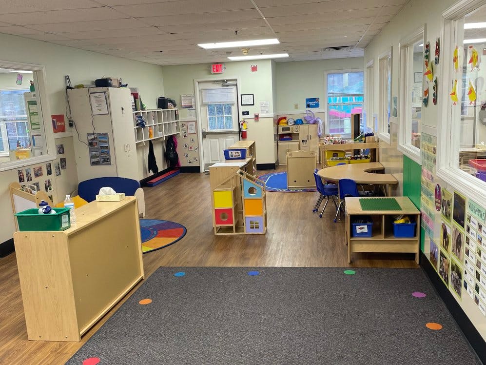 Empty classroom with small tables, chairs, and shelves