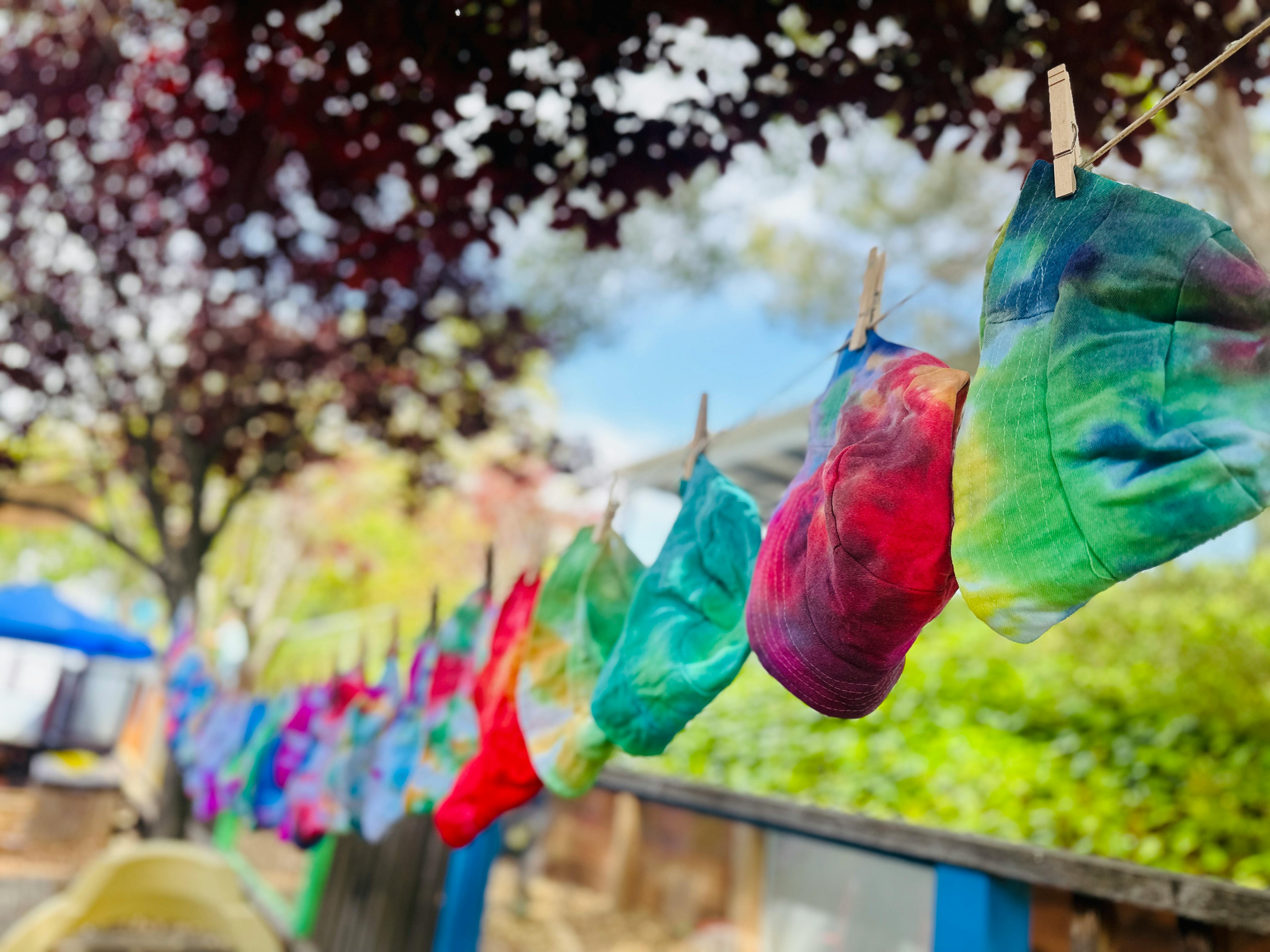 Tie-dye fabric squares hanging on a clothesline outdoors