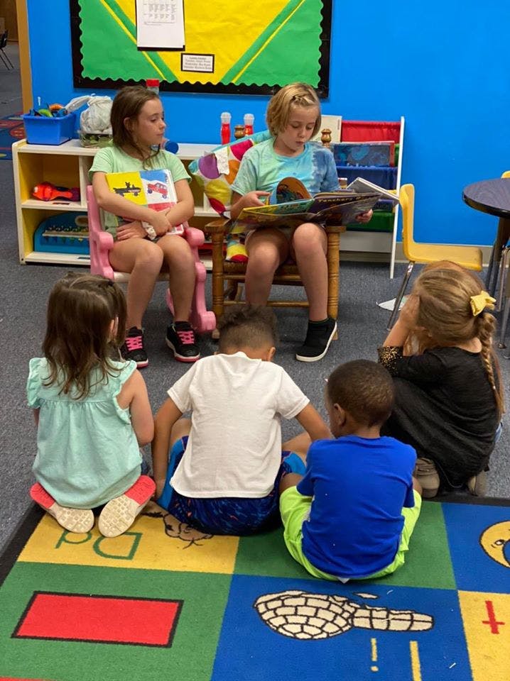 Children sitting on the floor and in chairs, looking at books