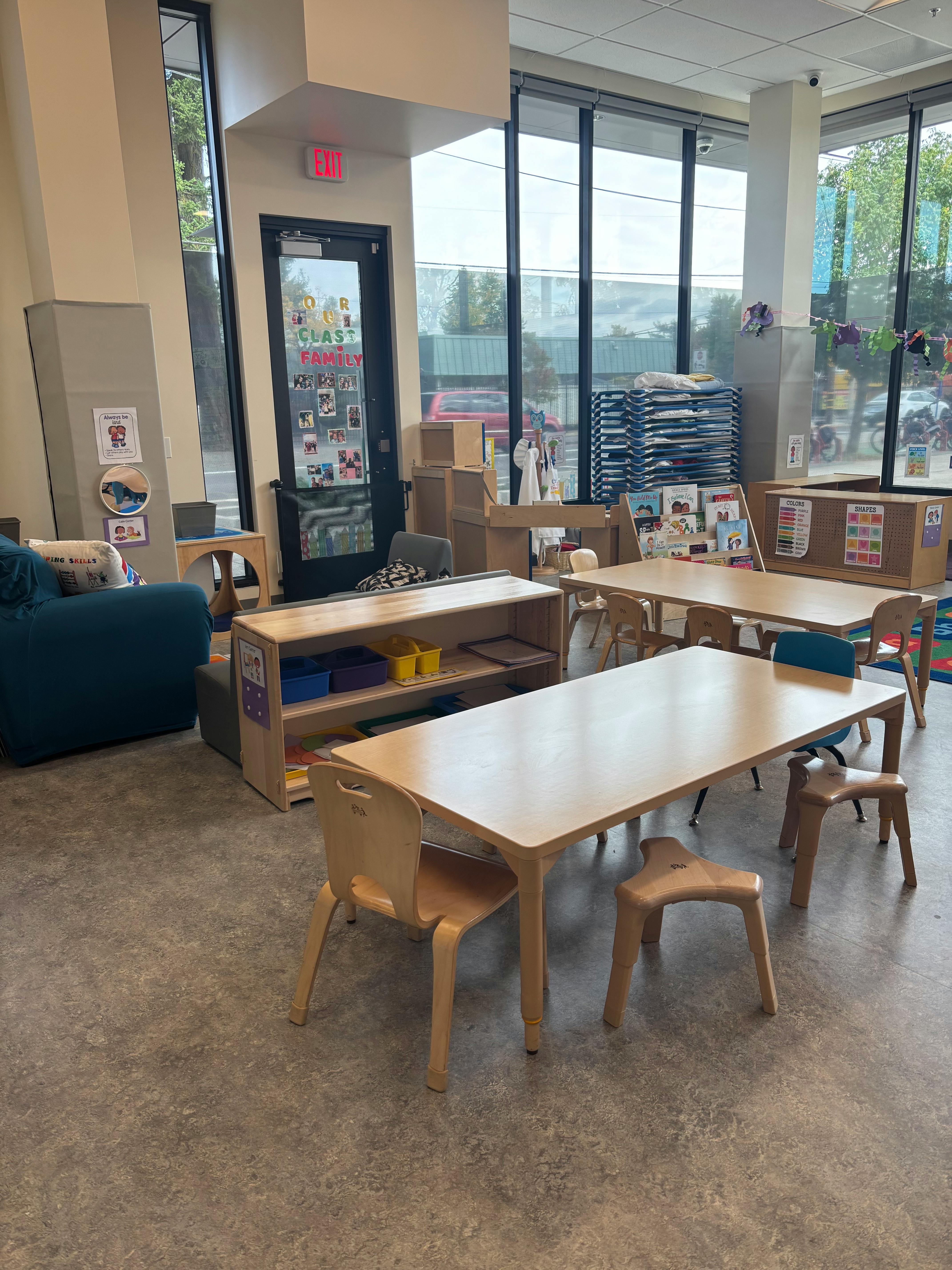 Classroom with small tables and chairs, shelves, and large windows