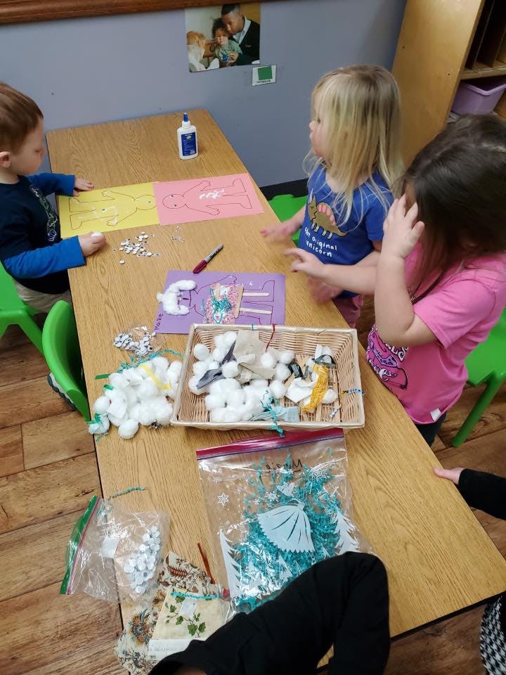 Three children at a table with craft supplies