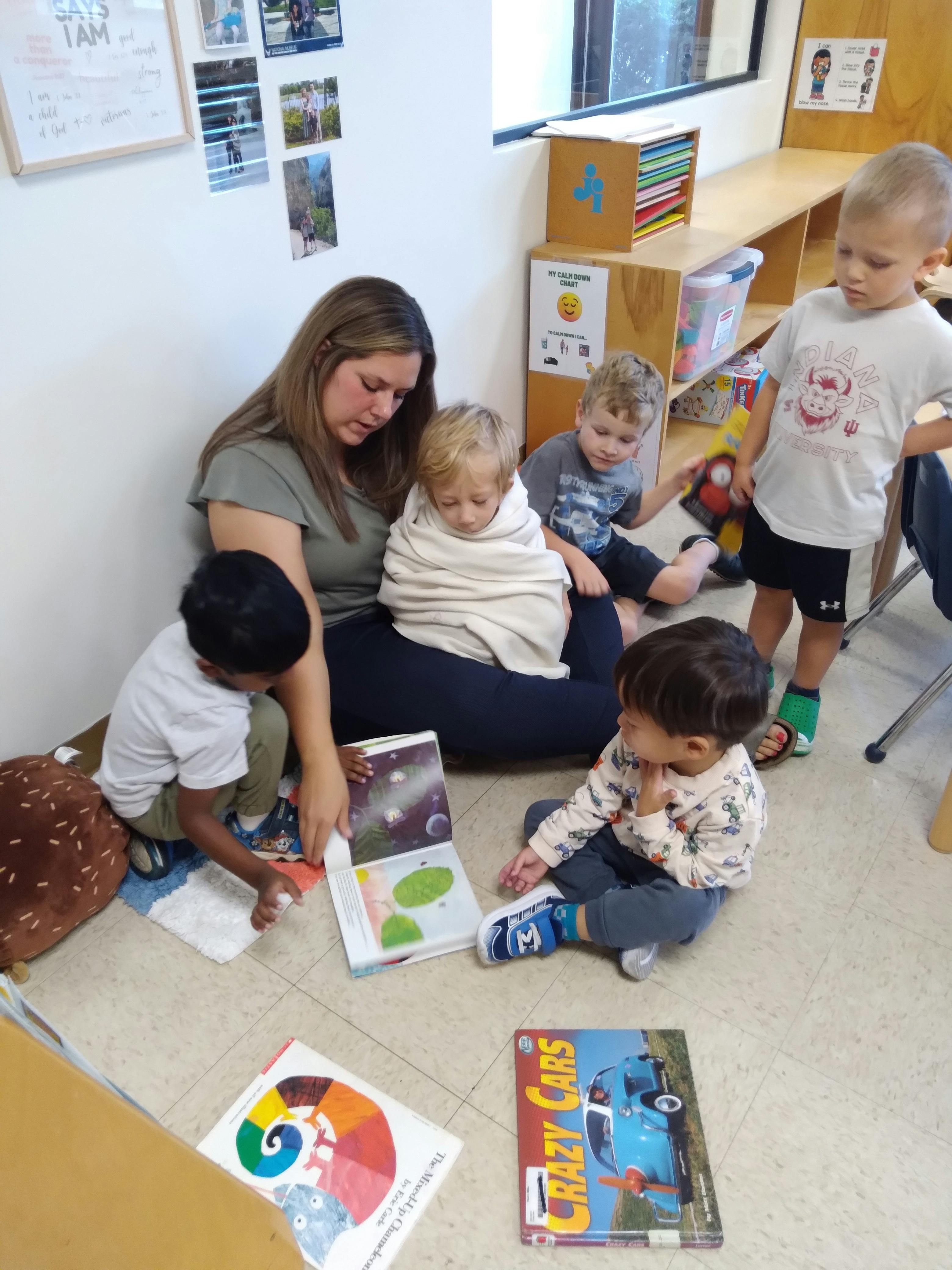 A person reading a book to a group of children in a classroom
