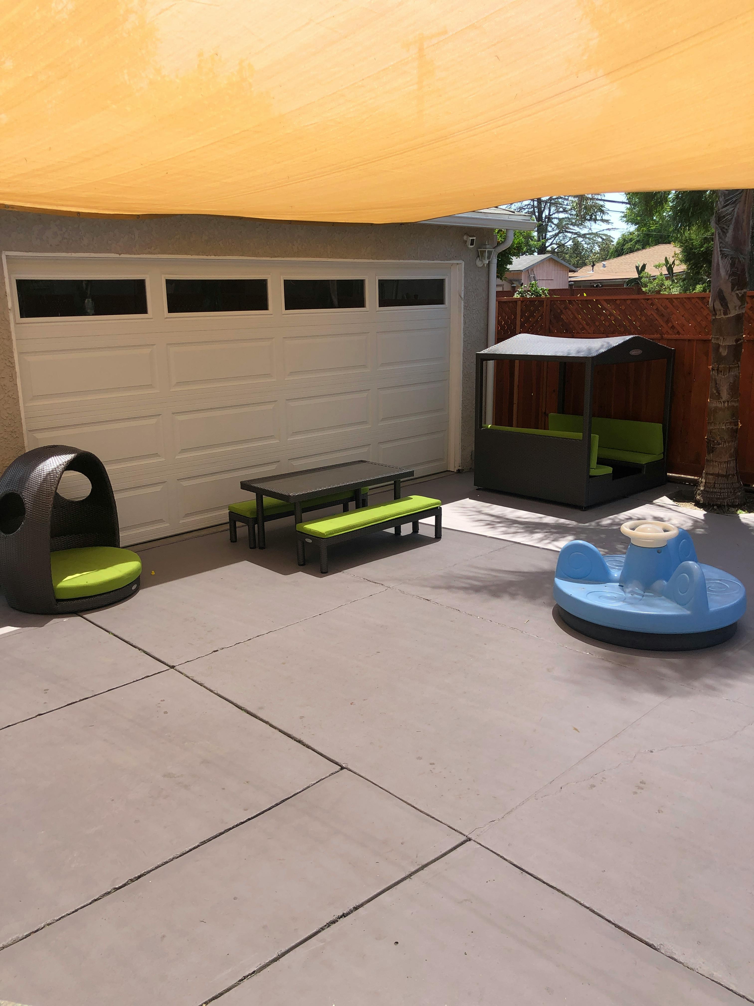 Patio with outdoor furniture and play equipment under a shade sail