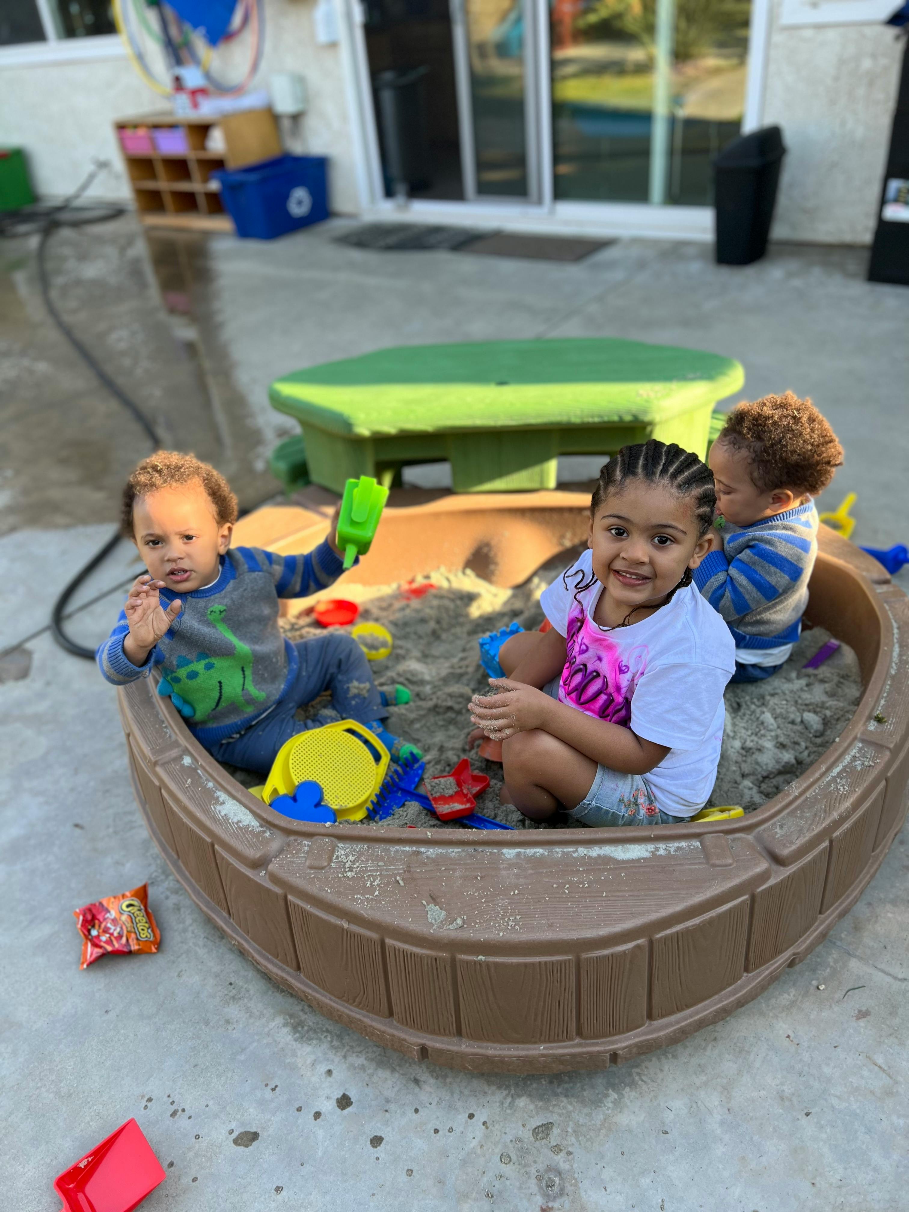 Three children playing in a sandbox