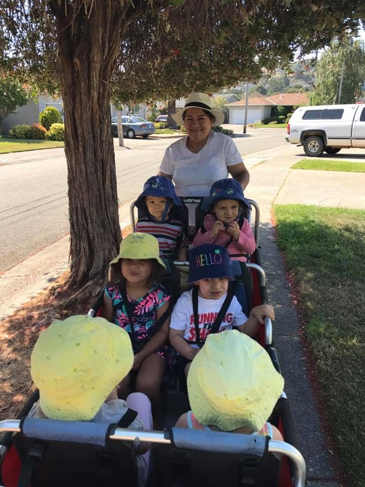 Person pushing a stroller with multiple children