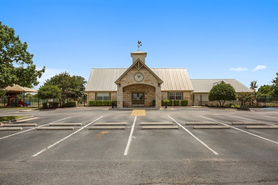 Building with a stone facade and metal roof, with a parking lot in the foreground