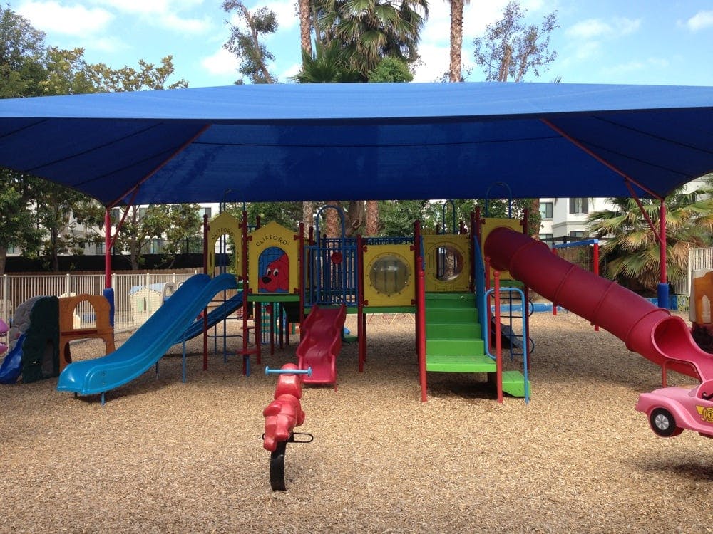 Playground with slides, climbing structures, and a blue shade canopy